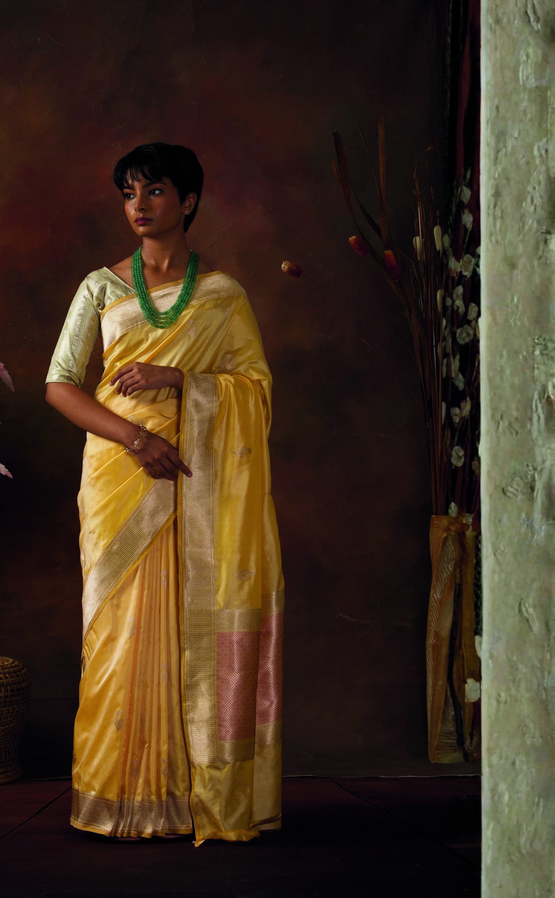 Woman in a luminous yellow handwoven silk saree with a detailed gold border