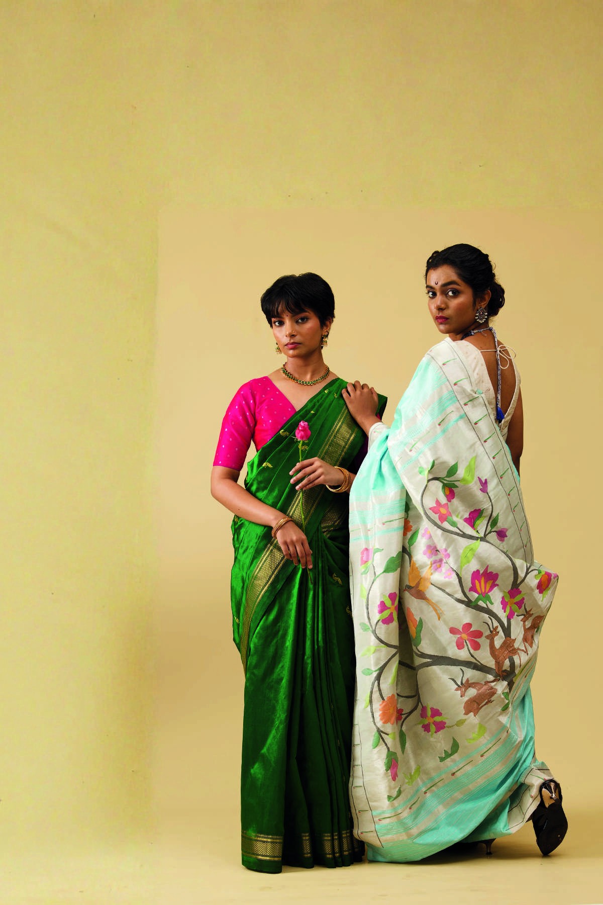 Two women wearing green and ivory silk sarees